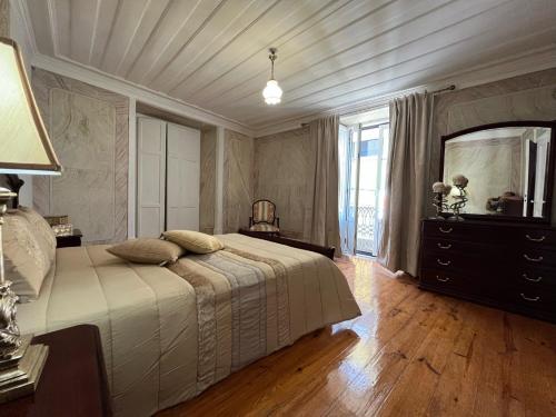 a bedroom with a bed and a dresser and a mirror at Alojamento VINTAGE BAIXA - TOMAR in Tomar