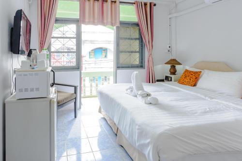 a bedroom with a large white bed and a television at High5 Guesthouse in Pattaya Central