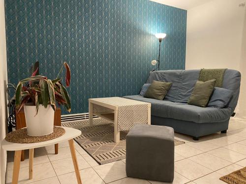 a living room with a blue couch and a table at Appartement cosy près de la gare avec parking in Saint-Pierre-des-Corps