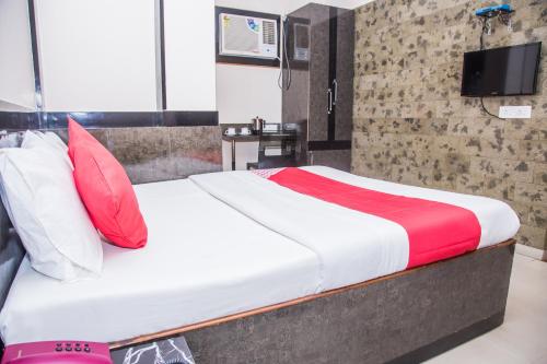Bett mit roten und weißen Kissen in einem Zimmer in der Unterkunft OYO Hotel Executive Inn in Agartala