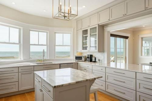 a kitchen with white cabinets and a large island at 1103 E Arctic - Salty Lady - Beautiful Custom Oceanfront Home - Hot tub in Folly Beach