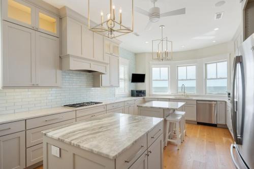 a kitchen with white cabinets and a large island at 1103 E Arctic - Salty Lady - Beautiful Custom Oceanfront Home - Hot tub in Folly Beach