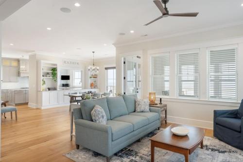 a living room with a blue couch and a kitchen at 1103 E Arctic - Salty Lady - Beautiful Custom Oceanfront Home - Hot tub in Folly Beach