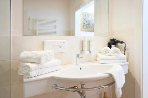 a bathroom with a sink and a mirror and towels at Appartementhaus Casamarai in Saalbach Hinterglemm