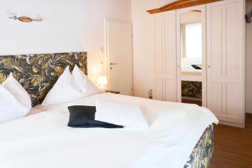 a bedroom with a white bed with a black pillow at Appartementhaus Casamarai in Saalbach Hinterglemm