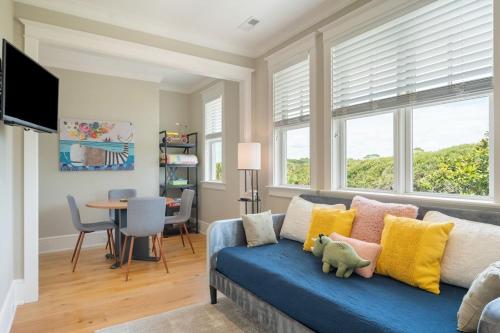 a living room with a blue couch with yellow and pink pillows at 1103 E Arctic - Salty Lady - Beautiful Custom Oceanfront Home - Hot tub in Folly Beach