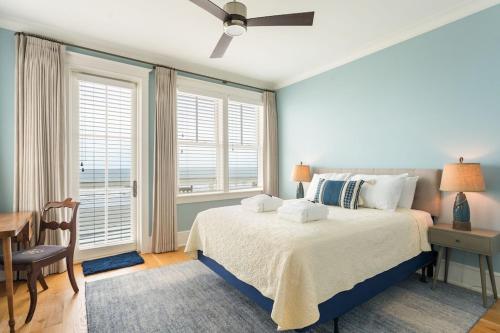 a bedroom with a bed and a desk and windows at 1103 E Arctic - Salty Lady - Beautiful Custom Oceanfront Home - Hot tub in Folly Beach