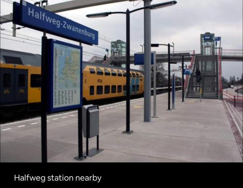 a yellow train at a train station with a sign at Wellness bungalow with jacuzzi &sauna&private garden near Amsterdam in Vijfhuizen