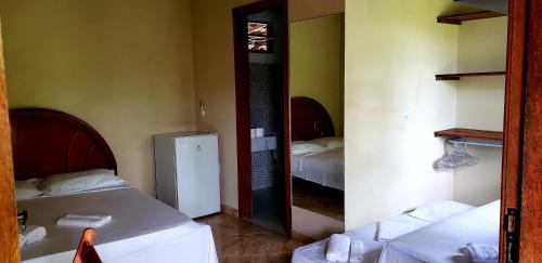 een kamer met 2 bedden en een spiegel bij Casa das Carpas in Arraial d'Ajuda