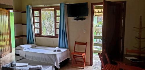 een slaapkamer met een bed, een tv en een raam bij Casa das Carpas in Arraial d'Ajuda