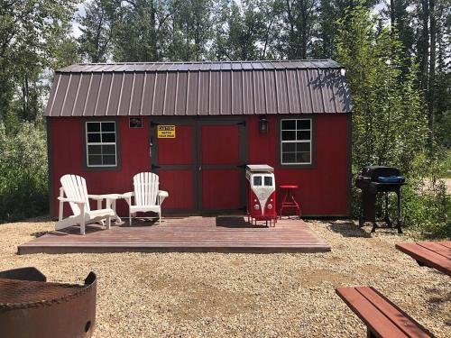 a red shed with two chairs and a table and a grill at Elevated Experience Camping Inc. Willey West in Drayton Valley