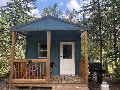 a blue shed with a porch and a white door at Elevated Experience Camping Inc. Willey West in Drayton Valley