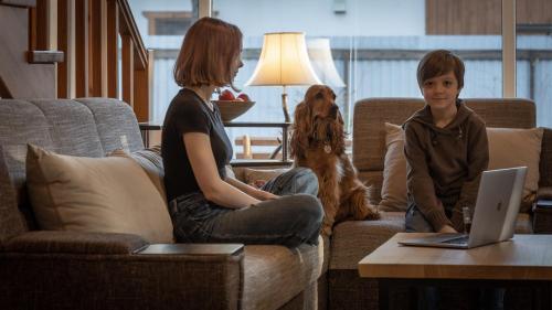 a boy and a girl sitting on a couch with a laptop at Ekodom in Voropayev