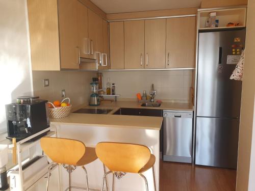 cocina con 2 sillas y nevera en vista al mar Habitacion en apartamento compartido, en Moraira