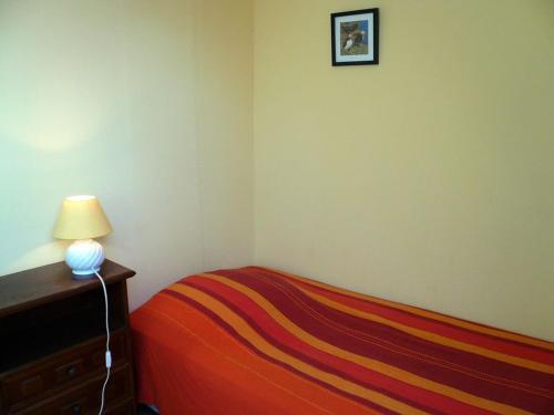 une chambre avec un lit et une lampe sur une commode dans l'établissement Charmante maison avec jardin, terrasse et parking à 2 km de Le Palais - Animaux acceptés - FR-1-418-221, au Palais