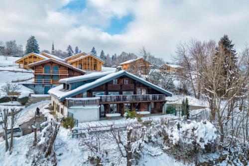 une maison en rondins dans la neige avec des arbres enneigés dans l'établissement Appartement La Pause de l'Ours - Welkeys, à Combloux