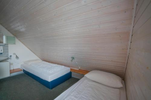 Habitación pequeña con 2 camas en una pared de madera. en Ferienhaus am See im Bergland, en Kirchheim
