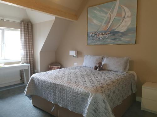 um quarto com uma cama com um urso de peluche sentado sobre ele em Maple Cottage B&B em Gullane