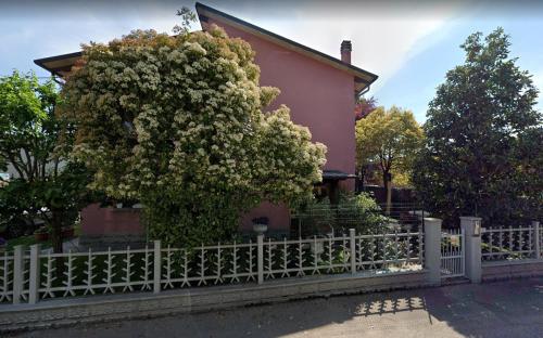 a tree in front of a pink house with a fence at Affittacamere da Alina in Argelato