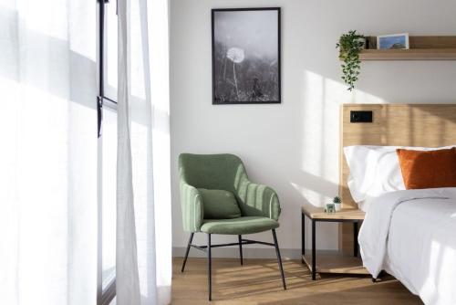 a bedroom with a green chair next to a bed at Be Casa - Rivas in Rivas-Vaciamadrid