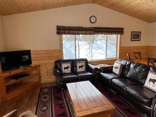 a living room with a leather couch and a tv at Faithful Street Inn in West Yellowstone