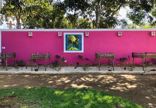 a pink wall with benches in front of a building at La Parcela Cunkal in Conkal