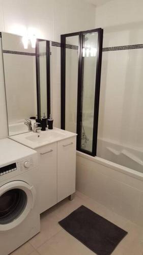 une salle de bain avec une machine à laver et un lavabo dans l'établissement Kanoperoz-Plage de Trestraou, à Perros-Guirec