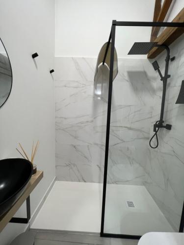 La salle de bains est pourvue d'une douche et d'un mur en marbre blanc. dans l'établissement SUITES CHIC, à Herencia