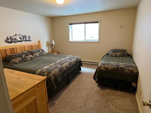a bedroom with two beds and a window at Faithful Street Inn in West Yellowstone