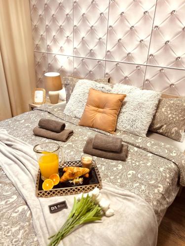 a tray of food and orange juice on a bed at Downtown Apartments Presley air-conditioned in Rzeszów