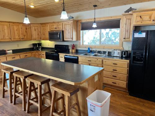 a kitchen with a black refrigerator and wooden cabinets at Faithful Street Inn in West Yellowstone