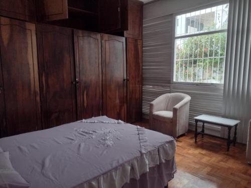 1 dormitorio con 1 cama, 1 silla y 1 ventana en Apartamento na Graça proximo a Barra e Hospitais, en Salvador