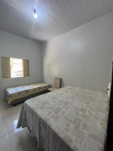 een witte slaapkamer met een bed en een raam bij CASA DE FÉRIAS in Barra do Garças