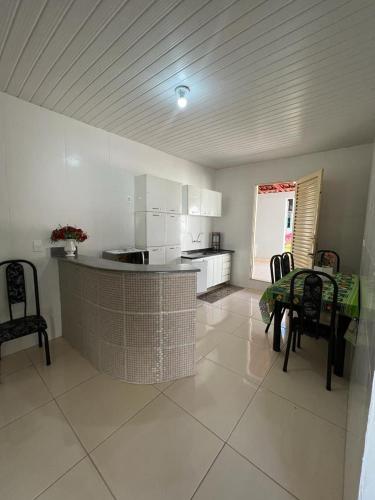 eine Küche mit einer Theke, einem Tisch und Stühlen in der Unterkunft CASA DE FÉRIAS in Barra do Garças