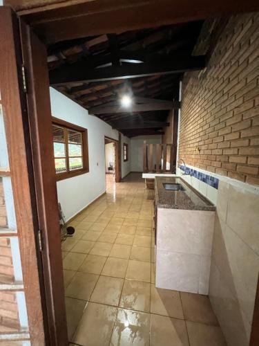 an empty room with a kitchen and a brick wall at Casa de Campo do Caminho da Fé in Águas da Prata