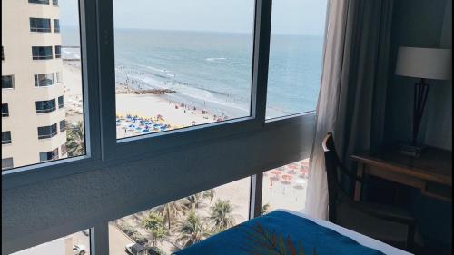 a bedroom with a view of the beach from a window at Hotel Almirante Cartagena Colombia in Cartagena de Indias