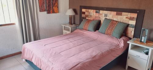 una camera da letto con un grande letto con una coperta rosa di El descanso, zona de bodegas a Ciudad Lujan de Cuyo