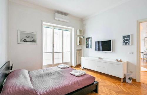 a white bedroom with a bed and a tv at Cicerone Apartment in Rome