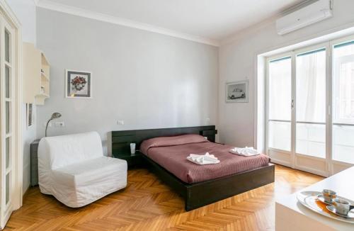 a bedroom with a bed and a white chair at Cicerone Apartment in Rome