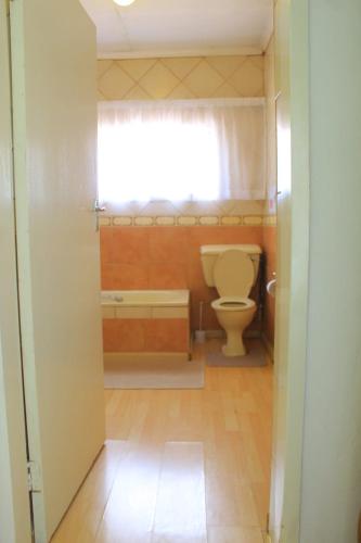 a bathroom with a toilet and a tub and a window at El Rose Guest House in Rustenburg