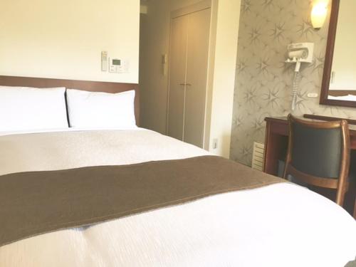 a bedroom with a white bed with two chairs and a desk at Kawasaki Hotel Park in Kawasaki