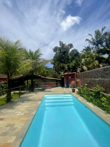 a blue swimming pool in front of a house at Aldeia de Camburi in Camburi