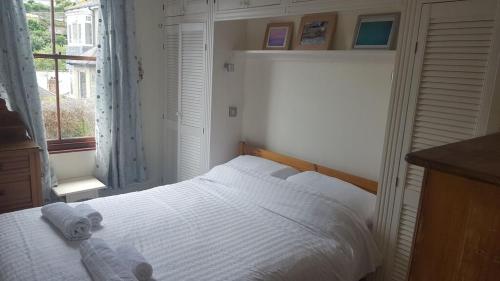 Un dormitorio con una cama blanca con toallas. en Stunning house with sea views and parking, Newlyn Penzance en Penzance