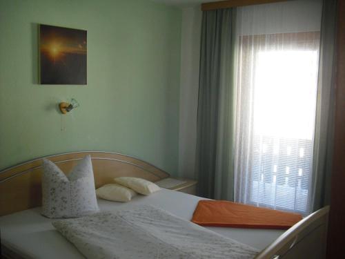 a bedroom with a white bed with a window at Pension Leitner in Hofen