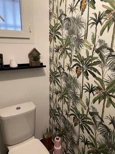 La salle de bains est pourvue de toilettes et de papier peint tropical. dans l'établissement Maison moderne cosy et lumineuse, à Saint-Christol-lès-Alès