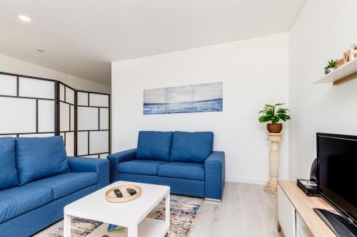 uma sala de estar com sofás azuis e uma televisão em DORA'S HOME em Cacilhas