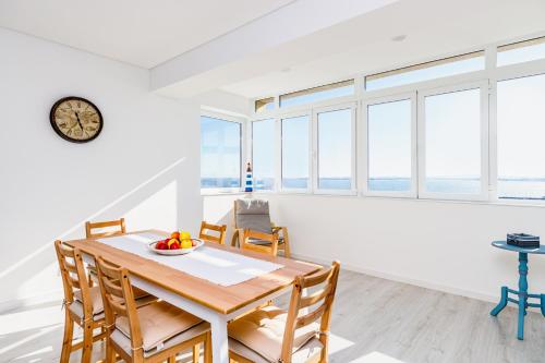 a dining room with a table and chairs and windows at DORA'S HOME in Almada
