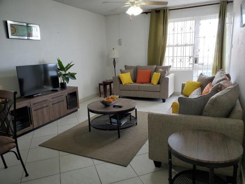 a living room with a couch and a tv at 1B Hastings Towers in Bridgetown