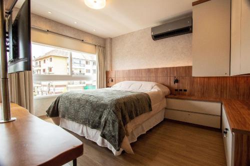 1 dormitorio con cama y ventana en Vita Boulevard 206-D - My Home Temporada, en Gramado