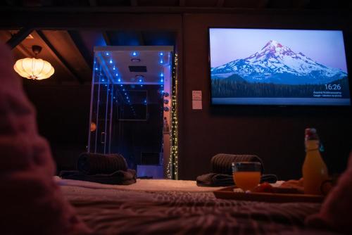 a room with a television with a mountain on the screen at PAUSE NATURE SORBAIS Chambre avec SPA, HAMMAM Shower, SAUNA, STREAMING et arrivée autonome in Sorbais